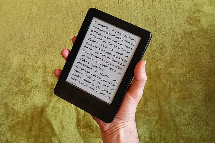 une personne tiens dans sa main sa kindle